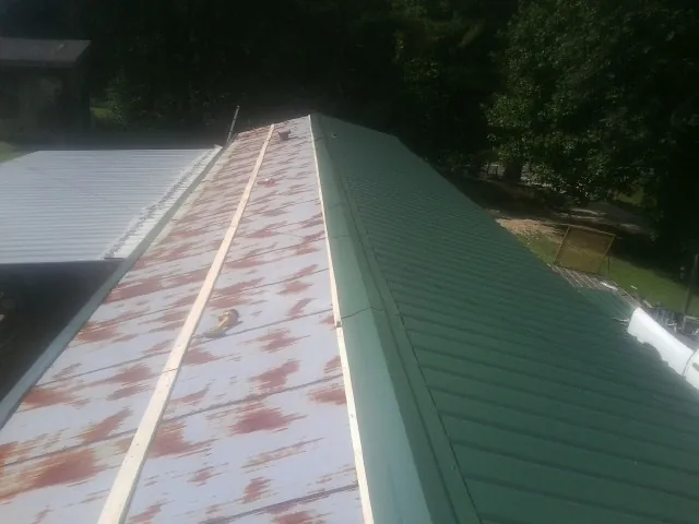 Old rusted panels beside newly installed green metal roofing — Wind Damage Roof Repair by Roofing Brothers in Higganum
