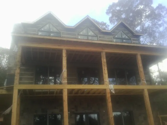 Dormers and porch framing on a large log home under construction — Roof Coating work by our crew in Higganum