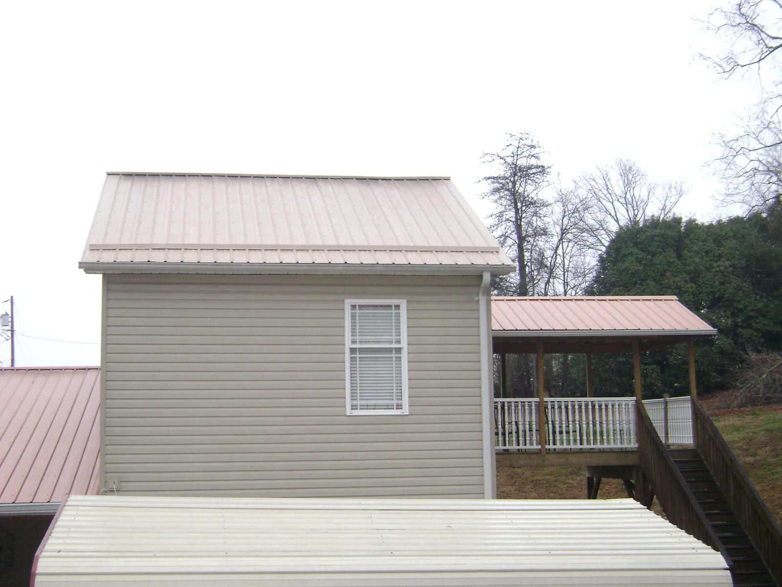 Tan metal roofs on a two story addition and attached porch, from a Roof Replacement job in Higganum